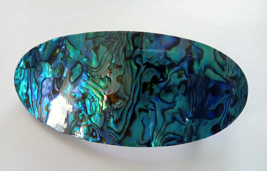 eliptical shape of paua clasp on white background, highlights beauty emanating from the shell.