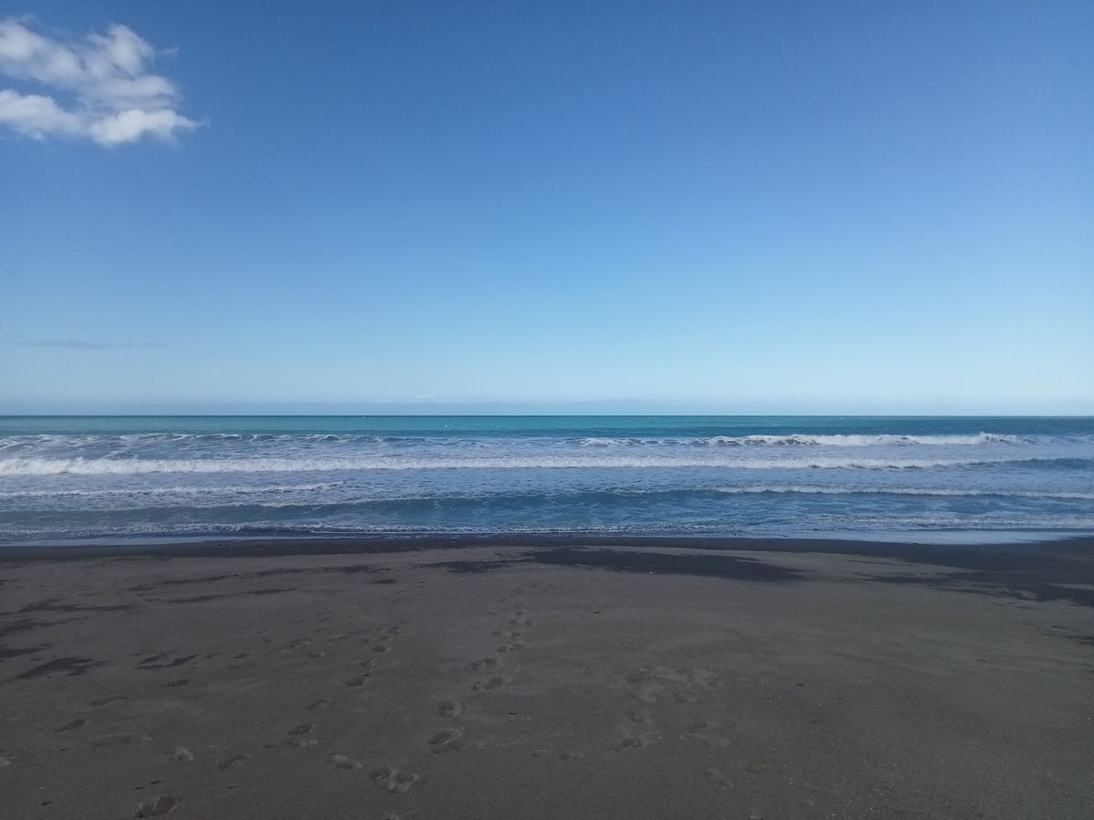 Beach with black sand and blue ocean under a clear sky
