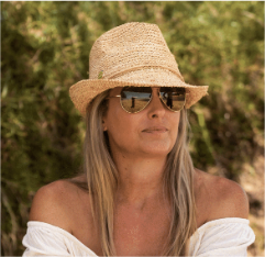 Woman wearing a straw hat and sunglasses with a blurred natural background
